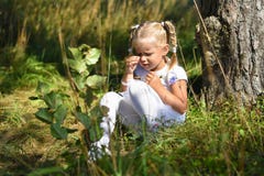 Lonely sad little girl in a white dress and a flower in her hand was lost in the woods, sitting near a tree and crying during day royalty free stock photos Lonely sad little girl in a white dress and a flower in her hand was lost in the woods, sitting near a tree and crying during day royalty free stock photos
