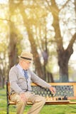 Lonely senior playing chess seated on bench Royalty Free Stock Photos Lonely senior playing chess seated on bench Royalty Free Stock Photos