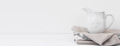 Long banner white vintage pitcher on stack of linen cotton towels. Kitchen interior home textile. Store header culinary site stock images Long banner white vintage pitcher on stack of linen cotton towels. Kitchen interior home textile. Store header culinary site stock images