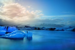 Long Exposure photography of blue iceberg floating in front of snow cap mountain stock image Long Exposure photography of blue iceberg floating in front of snow cap mountain stock image