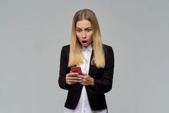 Long-haired blonde business lady in formal dress and white blouse holding a smartphone and is shocked to read the message stock images Long-haired blonde business lady in formal dress and white blouse holding a smartphone and is shocked to read the message stock images