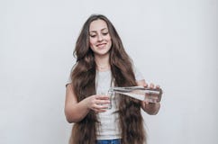 Long-haired girl pours water from bottle into glass