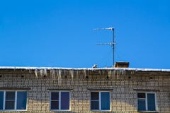 Long icicles and snow hang on the eaves of the house roof stock images Long icicles and snow hang on the eaves of the house roof stock images