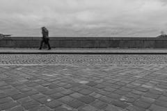 Longue exposition d'un piéton marchant sur un pont un jour pluvieux photographie stock libre de droits Longue exposition d'un piéton marchant sur un pont un jour pluvieux photographie stock libre de droits