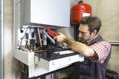 Loodgieter die een condenserende boiler herstellen royalty-vrije stock afbeelding Loodgieter die een condenserende boiler herstellen royalty-vrije stock afbeelding