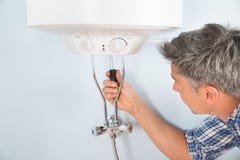 Loodgieter die waterverwarmer herstellen royalty-vrije stock fotografie Loodgieter die waterverwarmer herstellen royalty-vrije stock fotografie