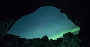 Looking through a cave entrance with aurora borealis