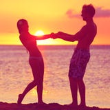 Los amantes juntan tener romance de la diversión en la playa de la puesta del sol imagenes de archivo Los amantes juntan tener romance de la diversión en la playa de la puesta del sol imagenes de archivo