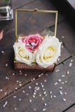 Los anillos de bodas de la novia y del novio están en una caja de cristal en las rosas, la caja están en la tabla de madera en el fotos de archivo Los anillos de bodas de la novia y del novio están en una caja de cristal en las rosas, la caja están en la tabla de madera en el fotos de archivo
