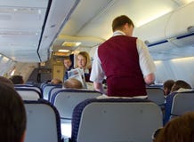 Los asistentes de vuelo dan a pasajeros la prensa fresca Fotos de archivo libres de regalías Los asistentes de vuelo dan a pasajeros la prensa fresca Fotos de archivo libres de regalías