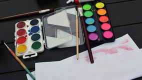 Los cepillos y las pinturas de colores brillantes con el papel están en la tabla fotos de archivo libres de regalías Los cepillos y las pinturas de colores brillantes con el papel están en la tabla fotos de archivo libres de regalías