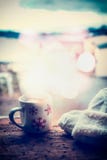 Los copos de nieve asaltan con la bebida caliente, las manoplas que hacen punto y el bokeh en travesaño de la ventana de la helad fotografía de archivo Los copos de nieve asaltan con la bebida caliente, las manoplas que hacen punto y el bokeh en travesaño de la ventana de la helad fotografía de archivo