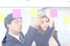 Los hombres de negocios asi?ticos jovenes utilizan notas de post-it sobre la pared de cristal para compartir idea en la sala de r imágenes de archivo libres de regalías Los hombres de negocios asi?ticos jovenes utilizan notas de post-it sobre la pared de cristal para compartir idea en la sala de r imágenes de archivo libres de regalías