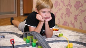 Los juegos de niños con el ferrocarril del ` s de los niños Un adolescente en la sala de juegos, jugando con un sistema de la con almacen de video Los juegos de niños con el ferrocarril del ` s de los niños Un adolescente en la sala de juegos, jugando con un sistema de la con almacen de video