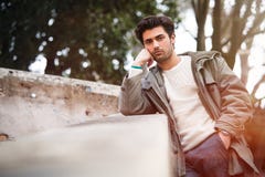 Los jóvenes hermosos aburrieron al hombre que se inclinaba en una pared outdoor fotos de archivo libres de regalías Los jóvenes hermosos aburrieron al hombre que se inclinaba en una pared outdoor fotos de archivo libres de regalías