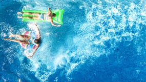 Los niños en fom aéreo de la opinión del abejón de la piscina arriba, los niños felices nadan en el buñuelo inflable del anillo y imagenes de archivo Los niños en fom aéreo de la opinión del abejón de la piscina arriba, los niños felices nadan en el buñuelo inflable del anillo y imagenes de archivo