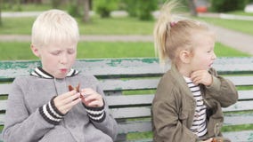 Los ni?os se sientan en un banco en el parque metrajes Los ni?os se sientan en un banco en el parque metrajes