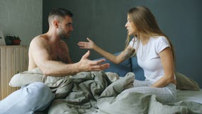 Los pares jovenes trastornados en sentarse en cama trastornan y se discuten foto de archivo libre de regalías Los pares jovenes trastornados en sentarse en cama trastornan y se discuten foto de archivo libre de regalías
