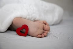 Los pies de los niños con un corazón rojo para el día de fiesta para la enhorabuena fotos de archivo Los pies de los niños con un corazón rojo para el día de fiesta para la enhorabuena fotos de archivo