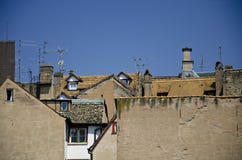 Los tejados con los áticos, las tablas rojas y las antenas en fondo del cielo azul imagen de archivo libre de regalías Los tejados con los áticos, las tablas rojas y las antenas en fondo del cielo azul imagen de archivo libre de regalías