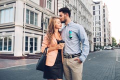 Lovely couple walking around British quarter. Dark-haired man in blue shirt kissing in head blonde girl in black dress royalty free stock photos Lovely couple walking around British quarter. Dark-haired man in blue shirt kissing in head blonde girl in black dress royalty free stock photos