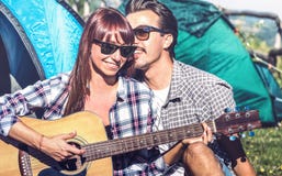 Lovers couple having fun outdoor cheering at camping place with vintage guitar - Young people enjoying summer time together stock images Lovers couple having fun outdoor cheering at camping place with vintage guitar - Young people enjoying summer time together stock images