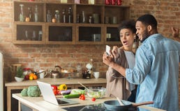 Loving black couple listening music during cooking dinner in kitchen