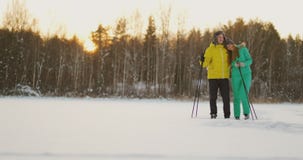 Loving man and woman skiing in the winter forest doing outdoor activities leading a healthy lifestyle. slow motion stock footage Loving man and woman skiing in the winter forest doing outdoor activities leading a healthy lifestyle. slow motion stock footage