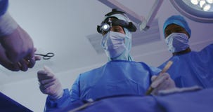 Low angle view of Middle-east female surgeon performing surgery in operation theater at hospital stock video footage Low angle view of Middle-east female surgeon performing surgery in operation theater at hospital stock video footage
