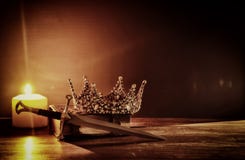 low key image of beautiful queen/king crown and sword. fantasy medieval period. Selective focus.