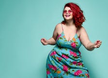 Lucky plus-size lady overweight woman in fashion sunglasses and colorful sundress happy dancing, celebrating