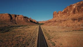 Luftschuß des Autofahrens entlang gerade amerikanische Wüstenlandstraßenstraße unter atmosphärischer felsiger Gebirgsschluchtkant Luftschuß des Autofahrens entlang gerade amerikanische Wüstenlandstraßenstraße unter atmosphärischer felsiger Gebirgsschluchtkant