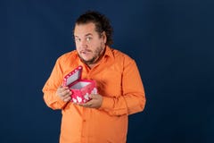 Lustiger dicker Mann im orange Hemd öffnet einen Kasten mit einem Geschenk lizenzfreie stockfotografie Lustiger dicker Mann im orange Hemd öffnet einen Kasten mit einem Geschenk lizenzfreie stockfotografie