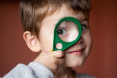 Lustiger Junge, der durch Lupe mit Überraschung schaut stockbilder Lustiger Junge, der durch Lupe mit Überraschung schaut stockbilder