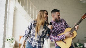 Lustiges glückliches und liebevolles Paartanzen und spielen Gitarre Mann und Frau haben Spaß während ihres Feiertags zu Hause stockbild Lustiges glückliches und liebevolles Paartanzen und spielen Gitarre Mann und Frau haben Spaß während ihres Feiertags zu Hause stockbild