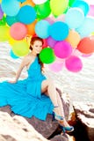 Luxury fashion woman with balloons in hand on the beach against