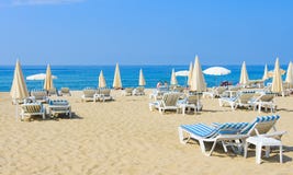 Luxury resort beach with umbrellas and sun beds on white sand near blue sea on bright sunny day Royalty Free Stock Photos Luxury resort beach with umbrellas and sun beds on white sand near blue sea on bright sunny day Royalty Free Stock Photos