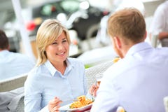 Lycklig affärskvinna som har mat med den manliga kollegan på den utomhus- restaurangen royaltyfri bild Lycklig affärskvinna som har mat med den manliga kollegan på den utomhus- restaurangen royaltyfri bild