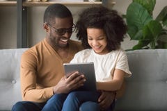 Lycklig afrikansk fader- och ungedotter som använder den digitala minnestavlan arkivfoton Lycklig afrikansk fader- och ungedotter som använder den digitala minnestavlan arkivfoton