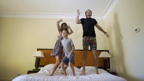 Lycklig familj med den lilla sonen som hemma hoppar p? s?ng arkivfilmer Lycklig familj med den lilla sonen som hemma hoppar p? s?ng arkivfilmer