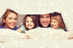 Lycklig familj med två ungar under filten hemma arkivfoto Lycklig familj med två ungar under filten hemma arkivfoto