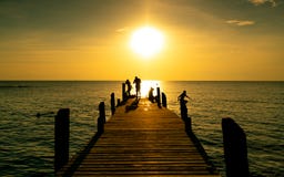Lycklig familjlek tillsammans på sommarsemester på träbron på solnedgången Förälder och barn som spelar på stranden på ferie arkivfoto Lycklig familjlek tillsammans på sommarsemester på träbron på solnedgången Förälder och barn som spelar på stranden på ferie arkivfoto