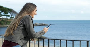 Lycklig flicka som använder en smart telefon i en balkong Lycklig flicka som använder en smart telefon i en balkong
