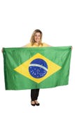 Lycklig kvinnlig fan med den brasilianska flaggan som rymmer en fotbollboll royaltyfria bilder Lycklig kvinnlig fan med den brasilianska flaggan som rymmer en fotbollboll royaltyfria bilder