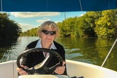 Lycklig le hög kvinna som kör motorbåten i floden, semesterloppbegrepp royaltyfria bilder Lycklig le hög kvinna som kör motorbåten i floden, semesterloppbegrepp royaltyfria bilder