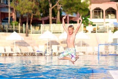 Lycklig pojkebanhoppning i simbassäng royaltyfri fotografi Lycklig pojkebanhoppning i simbassäng royaltyfri fotografi