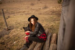 Lycklig ung kvinna som sitter med hennes svarta hund i fron av det gamla tr?huset royaltyfria bilder Lycklig ung kvinna som sitter med hennes svarta hund i fron av det gamla tr?huset royaltyfria bilder