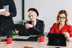 Lyckliga formgivare som tillsammans arbetar i deras kontor Två ung flickacoworkers som sitter på tabellen och arbetar under fotografering för bildbyråer Lyckliga formgivare som tillsammans arbetar i deras kontor Två ung flickacoworkers som sitter på tabellen och arbetar under fotografering för bildbyråer