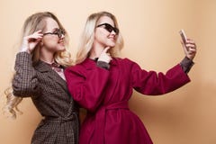 lyckliga två le flickor som gör selfiefotoet på smartphonen på beige bakgrund royaltyfri fotografi lyckliga två le flickor som gör selfiefotoet på smartphonen på beige bakgrund royaltyfri fotografi