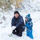 Lyckligt barn och farsa som har gyckel med insnöad vinter arkivfoton Lyckligt barn och farsa som har gyckel med insnöad vinter arkivfoton